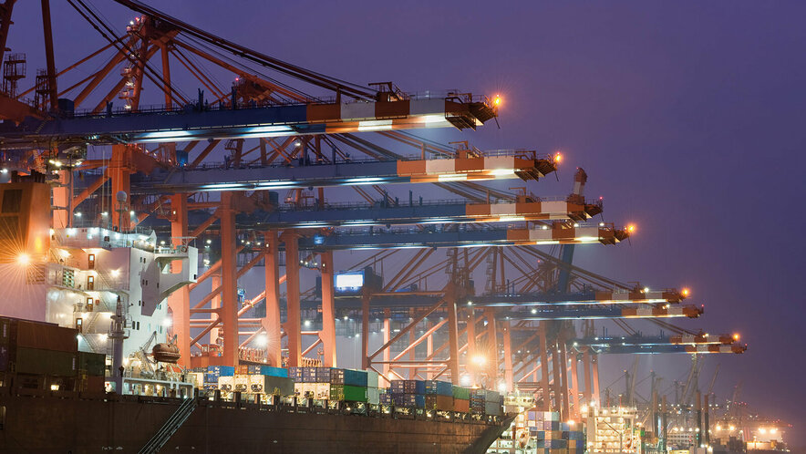 Beleuchteter Containerhafen bei Nacht.